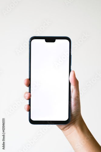 Business concept : Young man holding smartphone with blank screen on white background, closeup of hand, advertising text selling marketing products, mock up, Space for text.