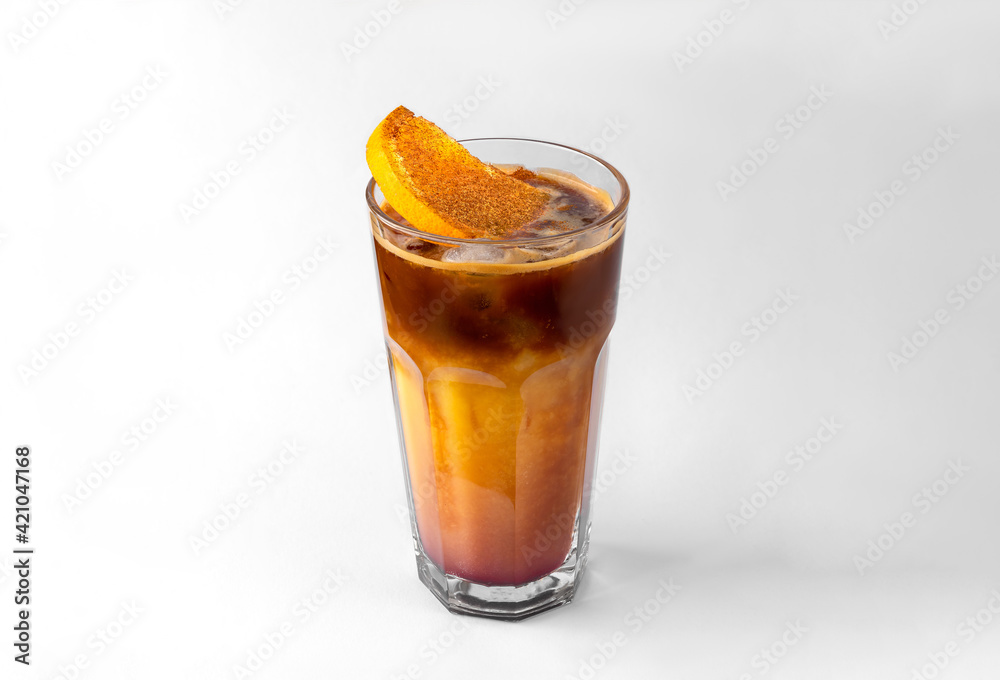 transparent glass of yellow refreshing summer drink with sliced orange, ice cubes and chocolate syrup