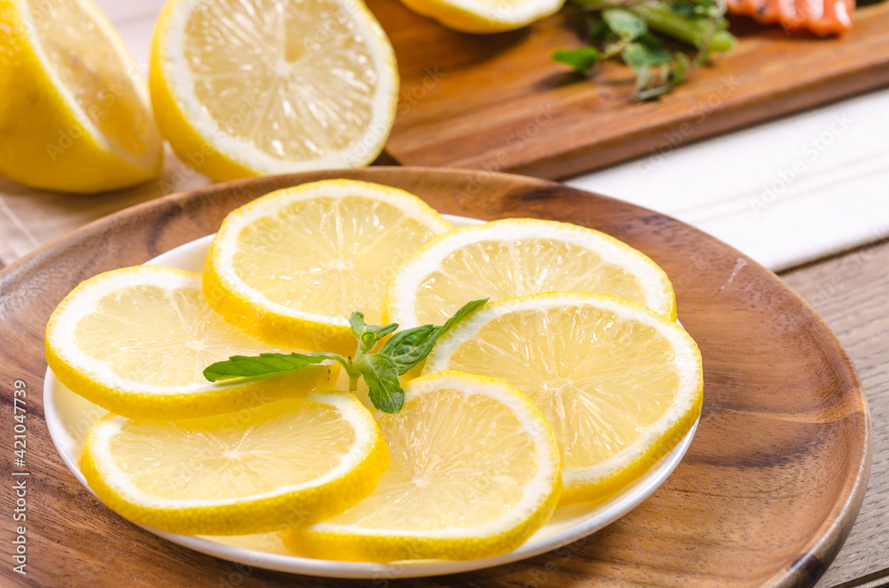 Close-up of fresh organic lemon with peppermint in the wooden plate on wood table. Close-up of fresh organic lemon with peppermint in the wooden plate on wood table.