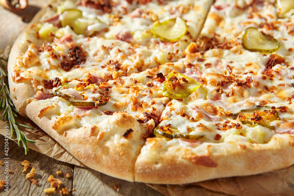 Tasty pizza with ham, gherkins, fried onions and pickle cucumber. Garnished on parchment with pizza ingredients on wooden table. Rustic style, sunlight. Tasty pizza with ham, gherkins, fried onions and pickle cucumber. Garnished on parchment with pizza ingredients on wooden table. Rustic style, sunlight.