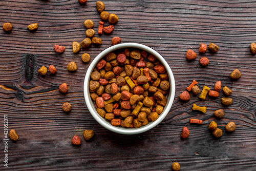 Fotografie dry dog food in bowl on wooden background top view