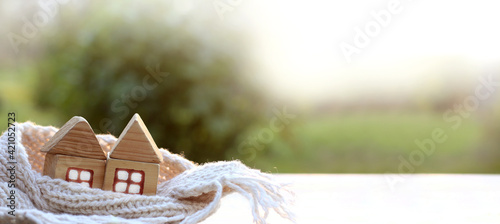 two wooden house in scarf on the background of a blurred landscape. cozy heating plan two in one