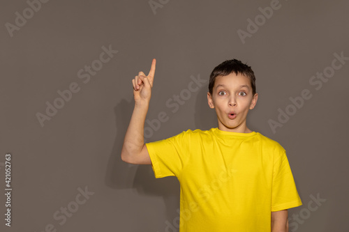 Yellow t-shirt mock up, Studio portrait of handsome young man teenager boy pointing excitedly to copyspace against gray background