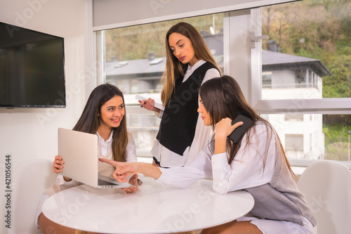 Young business girls in informal meeting with computer in white shirts. Informal breakfast at a table in the house