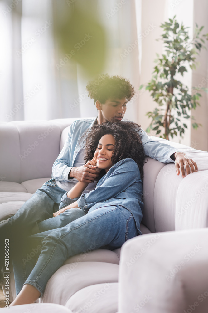 Smiling african american woman lying near boyfriend on couch Smiling african american woman lying near boyfriend on couch
