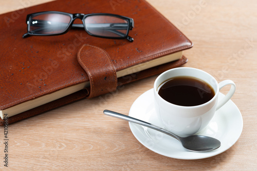 Brown leather notebook and glasses on table