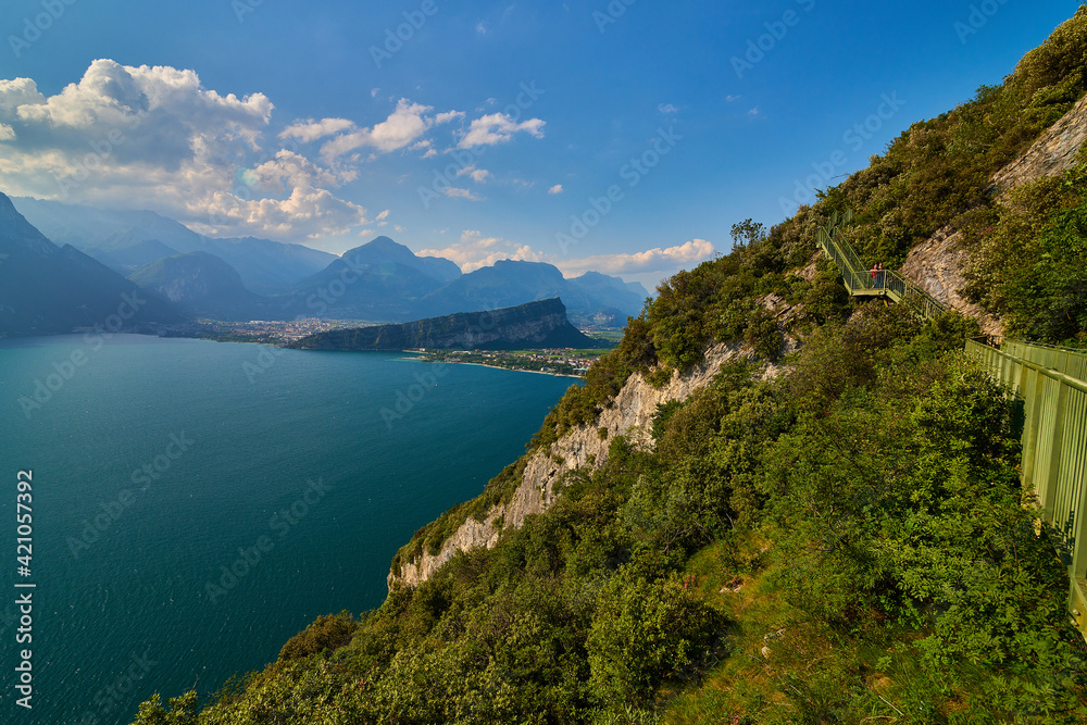 Panoramic view on Lake Garda from the Busatte-Tempesta trail near Nago-Torbole with the iron staircase,  Torbole  town surrounded by mountains in the summer time,Italy