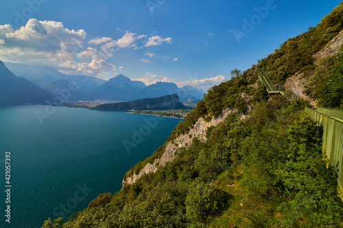 Panoramic view on Lake Garda from the Busatte-Tempesta trail near Nago-Torbole with the iron staircase,  Torbole  town surrounded by mountains in the summer time,Italy