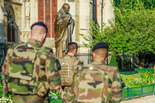 PARIS, FRANCE - JULY 1, 2017: Pope John Paul II statue guarding soldiers of National Armed Forces in Notre Dame of Paris, keeping security after recent terrorist attacks in Paris. photo