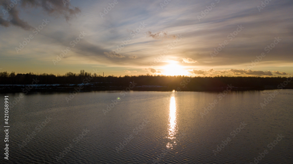 Aerial view of a beautiful and dramatic sunset over a forest lake reflected in the water, landscape drone shot. Blakheide, Beerse, Belgium. High quality photo