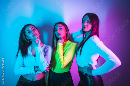 Lifestyle of friends partying in a disco with blue and pink neon lights, portrait of young Caucasian women