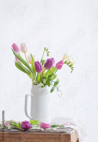 Fototapeta Naklejka Na Ścianę i Meble -  spring flowers on old chair on background old white wall