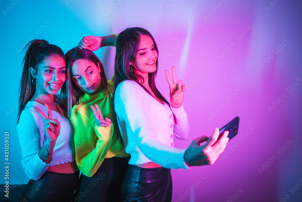 Lifestyle of friends partying in a disco with blue and pink neon lights, taking a selfie with the phone for social networks Lifestyle of friends partying in a disco with blue and pink neon lights, taking a selfie with the phone for social networks