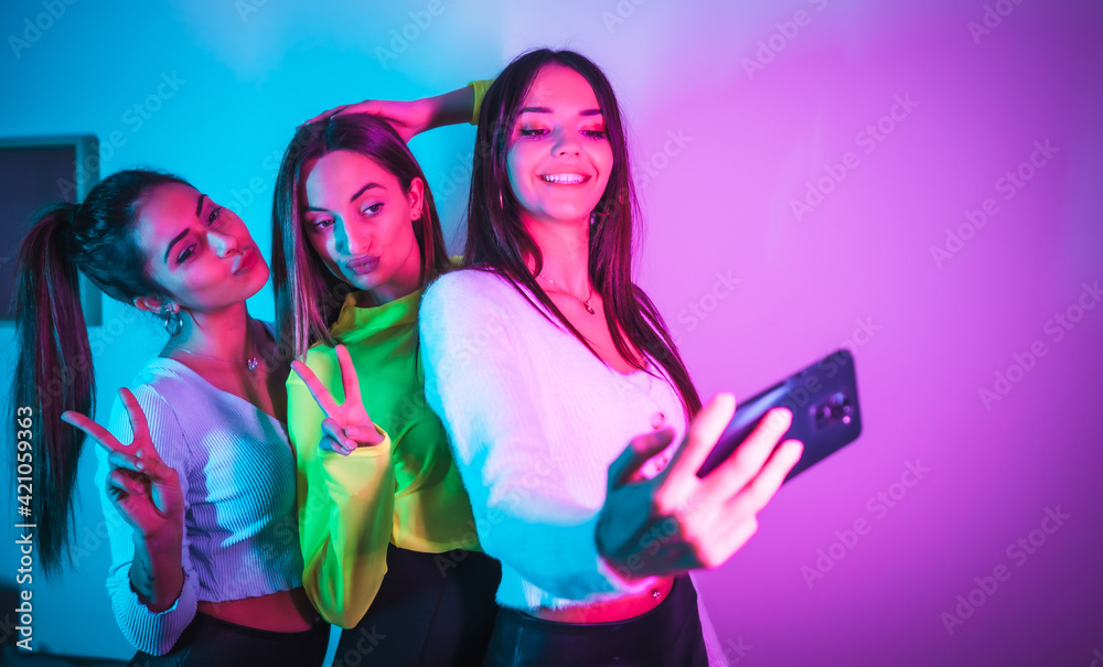 Lifestyle of friends partying in a disco with blue and pink neon lights, having fun taking a photo with the phone for social networks Lifestyle of friends partying in a disco with blue and pink neon lights, having fun taking a photo with the phone for social networks