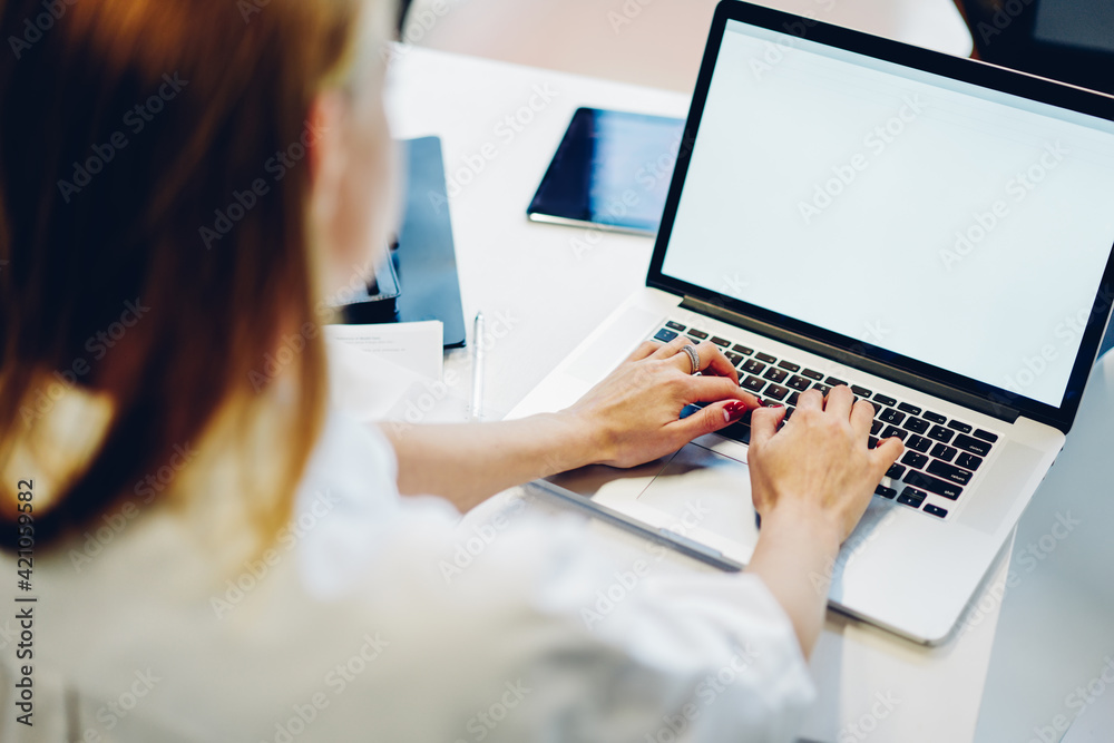 Faceless female freelancer working on computer in workplace