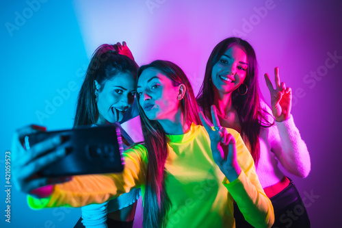 Lifestyle of friends partying in a disco with blue and pink neon lights, having fun taking a photo for social networks
