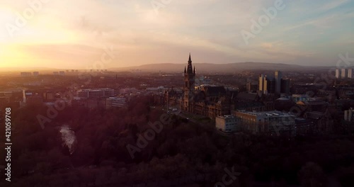 Flying in spring at sunset over the Kelvingrove park in Glasgow, Scotland towards the Gilbert Scott tower at Glasgow University.