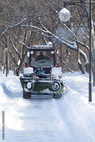 Tractor clears snow in the park in winter