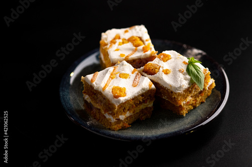 Carrot dessert cake on a plate on a black background.