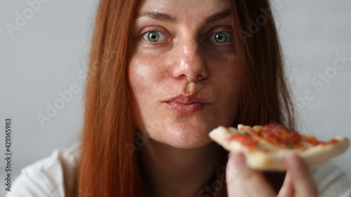 Young woman with long hair holding tasty big slice of pizza ready to eat at home