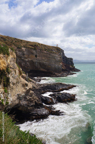 Scenic Cliff landscape with dramatic clouds and small lighthouse in the back