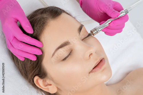 Cosmetologist makes procedure microdermabrasion on the face against acne and blackheads near the eyes. Women's cosmetology in the beauty salon.