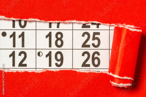 Red paper torn to reveal monthly calendar