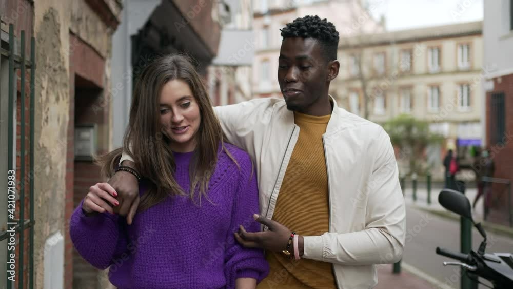Interracial young couple walking together in street. Black man embracing white girlfriend Interracial young couple walking together in street. Black man embracing white girlfriend