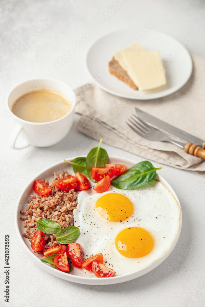 Eggs, buckwheat, tomatoes and spinach on a plate, coffee in cup. Healthy breakfast. Eggs, buckwheat, tomatoes and spinach on a plate, coffee in cup. Healthy breakfast.