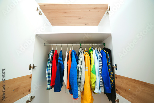 Kids clothing on the hangers. White modern closet inside. Storage organization. Order and cleanliness.