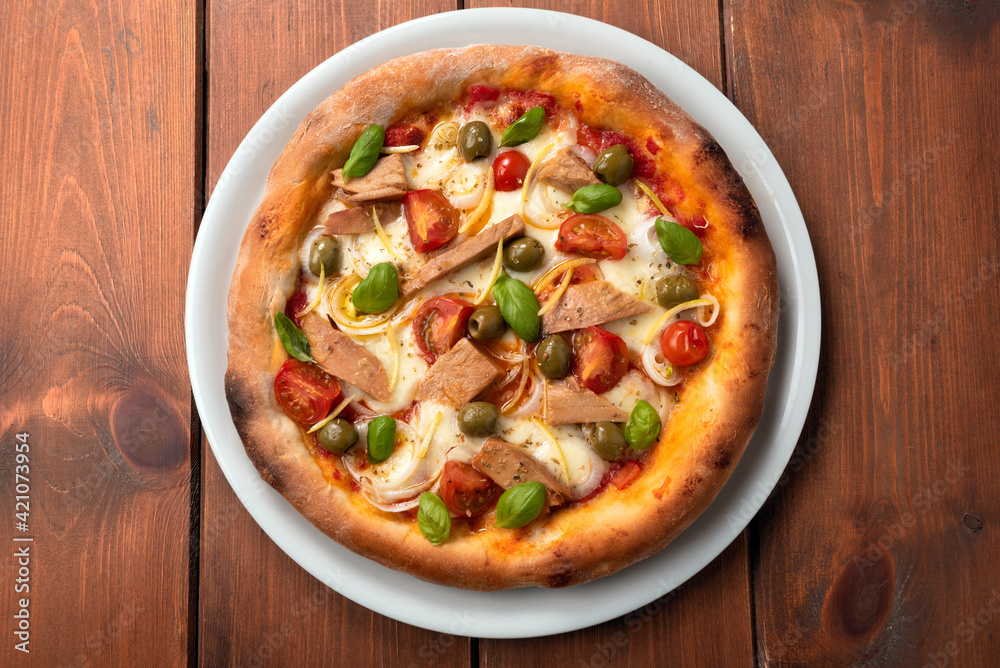 Deliziosa pizza gourmet con tonno pinne gialle, cipolle, pomodorini, olive e basilico fresco 