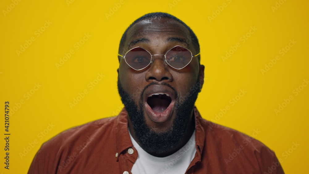 Portrait of surprised african american man posing on yellow background. Portrait of surprised african american man posing on yellow background.