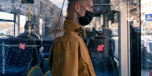 Coronavirus, covid -19, young man with respiratory mask traveling in the public transport by bus