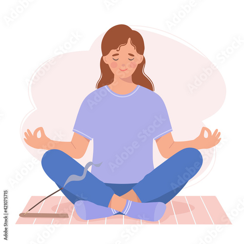 Young woman meditates sitting on a yoga mat.