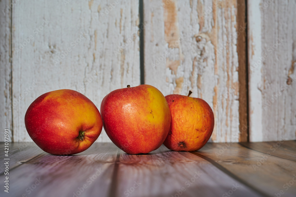 Apples lit from the sun decoratively lying on a wooden underground. Apples lit from the sun decoratively lying on a wooden underground.