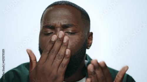 Closeup african man throwing air kiss from hand in grey background in studio.