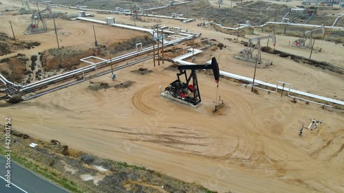 Aerial view around a hyudraulic pumpjack, pumping oil at a facility, in USA - orbit, drone shot