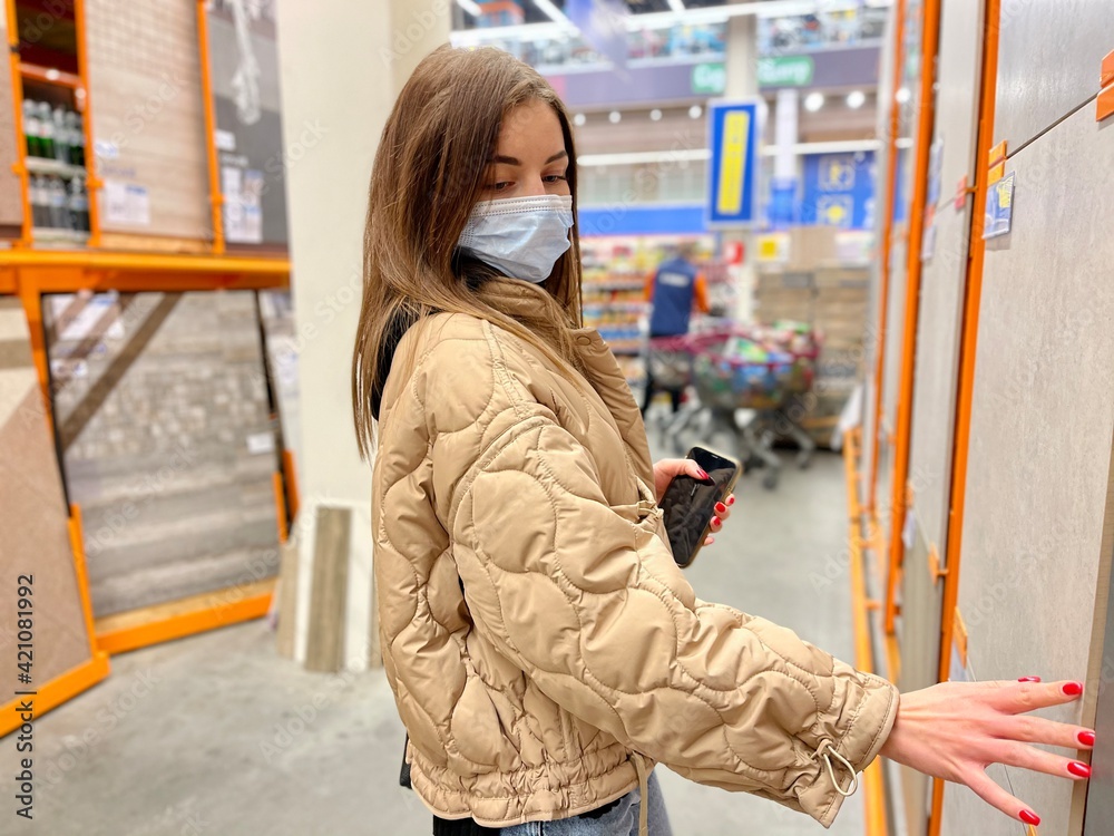 Fototapeta premium girl wearing a protective mask against coronavirus in a store