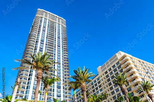 Oceanfront apartment skyscrapers buildings along coast in Miami Beach, Florida with green palm trees on sunny summer day