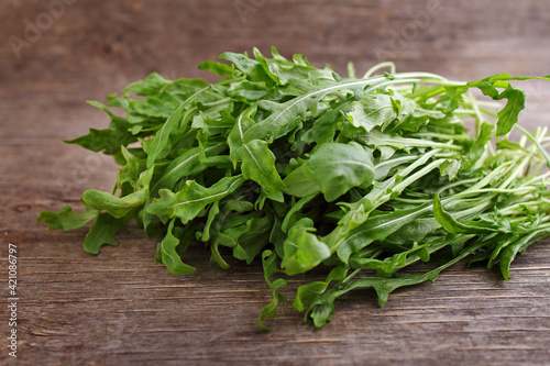 Healthy food concept with fresh organic arugula herb leaves on dark background.