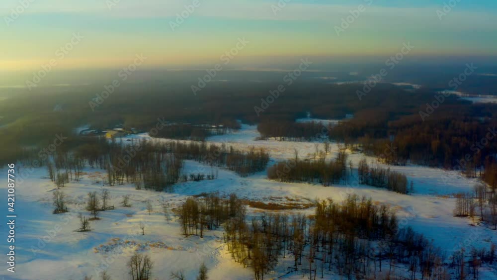 aerial parrallel flyover birds view of oval horizon of winter forest thick terrain covered with snow during sunny glow sunrise reflecting on the plains layered on blue green skies by a curvy road 5-6 aerial parrallel flyover birds view of oval horizon of winter forest thick terrain covered with snow during sunny glow sunrise reflecting on the plains layered on blue green skies by a curvy road 5-6