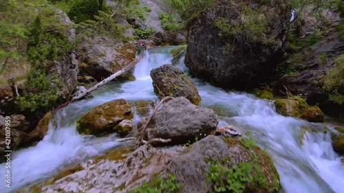 A beautiful flowing stream and small waterfall among boulders and rocks covered in moss and foliage. photo