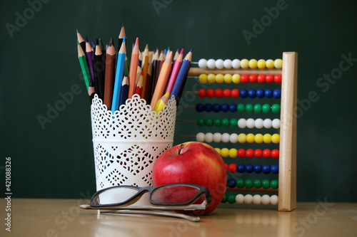 Blackboard with slide rule, pen, glasses, apple in classroom as background concept for education and elementary school.  photo