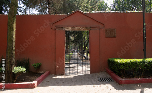 Puerta con reja, barda y árboles al fondo photo