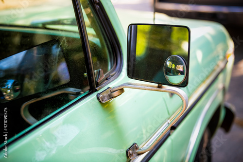 Closeup of green vintage retro style small car parked in Charleston, SC with reflection on side rear view mirror glass photo