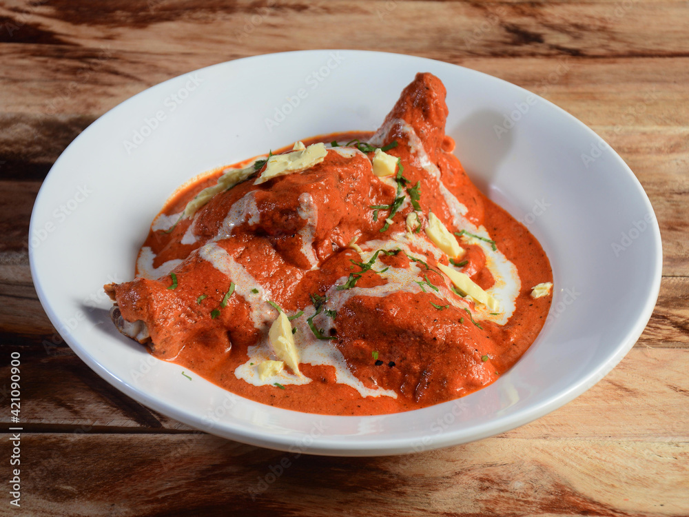 Indian Butter Chicken or Murgh Makhani in a bowl over a wooden rustic background. selective focus Indian Butter Chicken or Murgh Makhani in a bowl over a wooden rustic background. selective focus