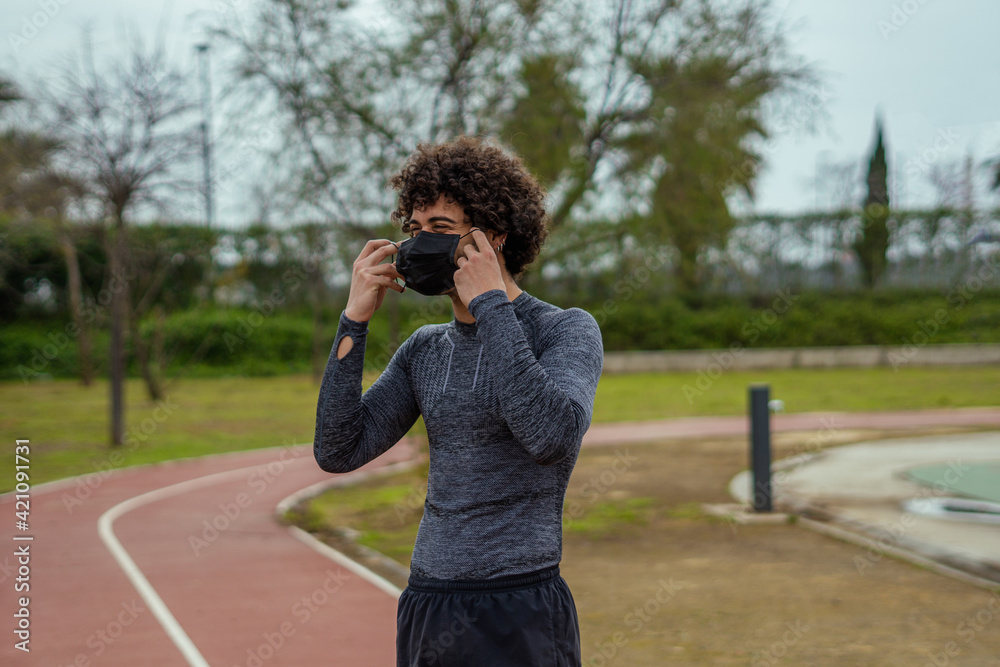 Happy young man in sports clothes smiling and playing with a mask. COVID. Happy young man in sports clothes smiling and playing with a mask. COVID.