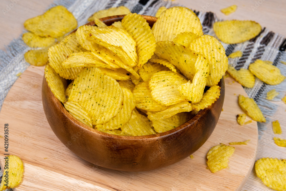 Fluted potato chips on a wooden bowl. Snack, ready meal menu, junk food. copyspace Fluted potato chips on a wooden bowl. Snack, ready meal menu, junk food. copyspace
