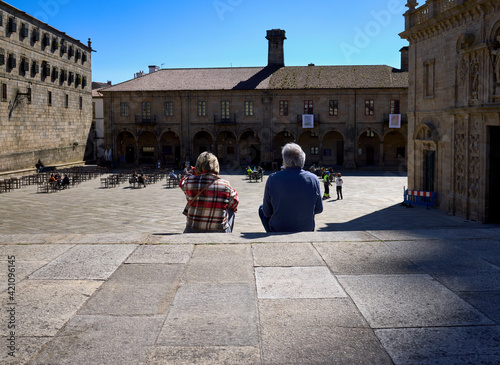 A man and a woman contemplate a city square sitting on a staircase