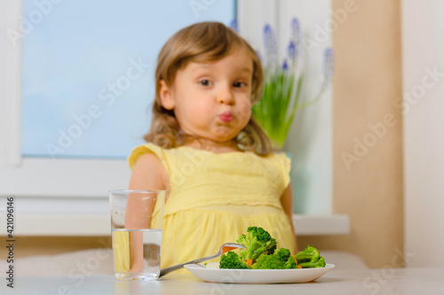 The child struggles with disgust and does not eat broccoli. Organic Cabbage and food on a plate.Green healthy vegetables